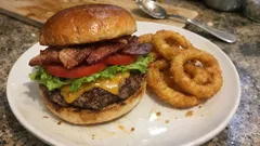 Hambúrguer New York com cheddar e bacon — e aros de cebola bem crocantes